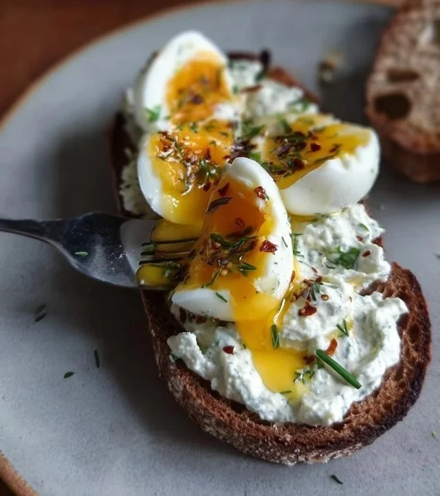 Creamy herbed Greek yogurt served with smashed eggs on a plate