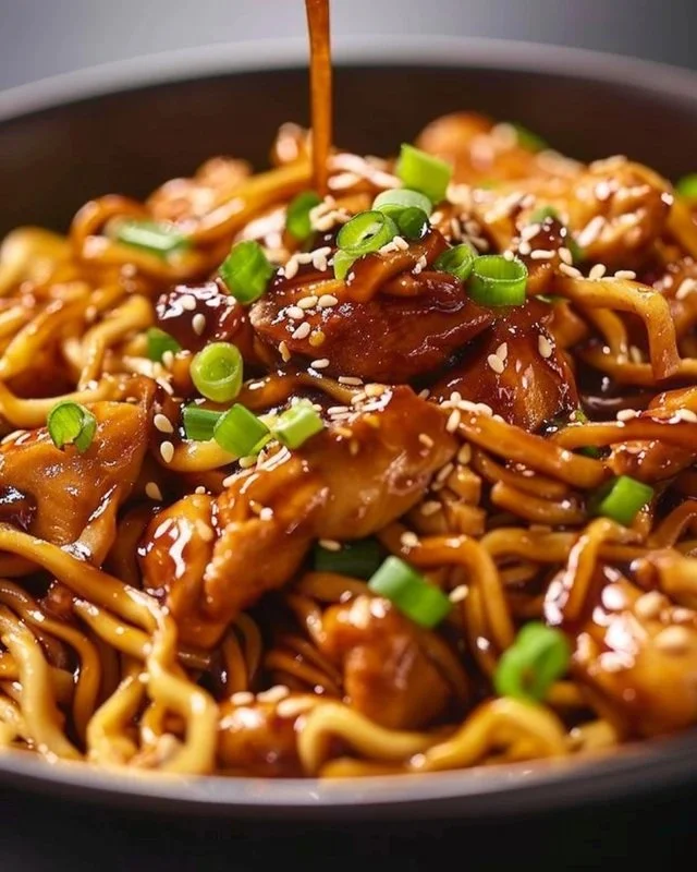 Plate of delicious sticky garlic chicken noodles garnished with scallions