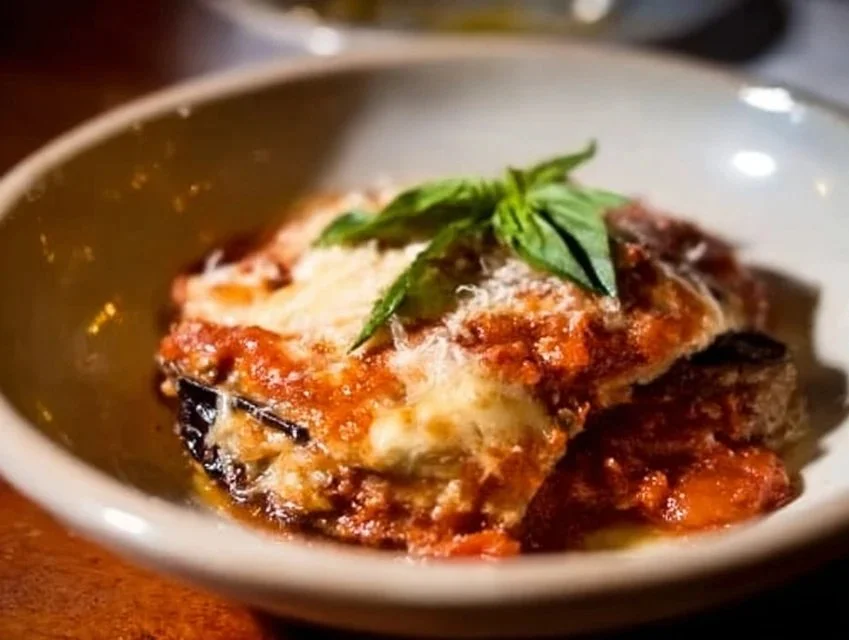 Delicious homemade Eggplant Parmesan served with marinara sauce and cheese