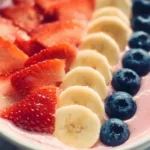 Bowl of colorful fruit smoothie topped with fresh fruits and seeds