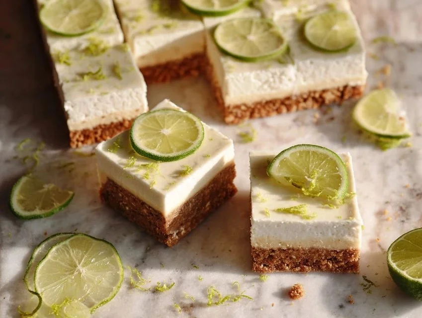 Delicious key lime pie bars topped with whipped cream on a white plate.